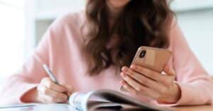 woman writing down information from her phone