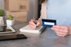 (woman writing down credit card information)