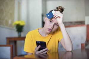 (stressed woman holding a credit card)