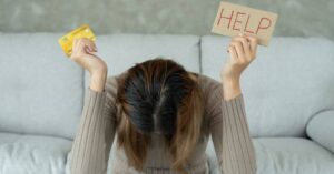 (woman holding a credit card and help sign indicating she’s struggling financially)