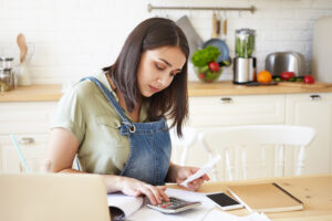 Person reviewing bills and using a calculator at a kitchen table